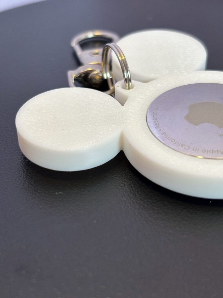 Front-facing white mouse-ear AirTag bag charm with attached metal clasp