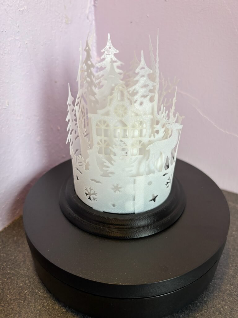 Festive lantern with layered snowy forest and cabin design
