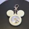 Front-facing white mouse-ear AirTag bag charm with attached metal clasp