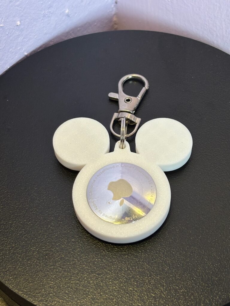 Front-facing white mouse-ear AirTag bag charm with attached metal clasp