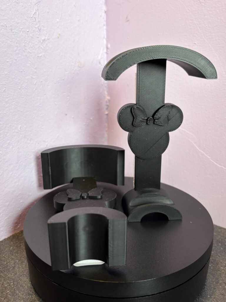 Black 3D-printed mouse ear wall hook with bow design on pink background