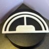White 3D-printed hat brim shaper keeping a cap curved on black surface