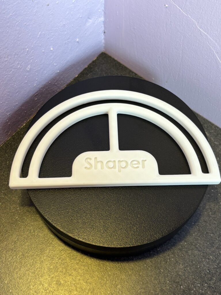 White 3D-printed hat brim shaper keeping a cap curved on black surface