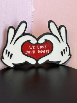 Magical cruise door gift decoration — 3D printed cartoon white gloved hands forming a heart with red centre reading "We Love Your Door!", black outline, UK made fish extender gift