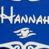 Close-up of personalised magical cruise stateroom door plaque showing "Hannah" in enchanted storybook font — blue and white 3D printed with ornate scroll detail and winged charm motif