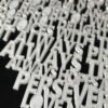 Close-up of raised 3D printed lettering on 1 Corinthians 13 scripture heart wall art — pearlescent white PLA showing "Always Trusts, Always Hopes, Perseveres, Love Never Fails