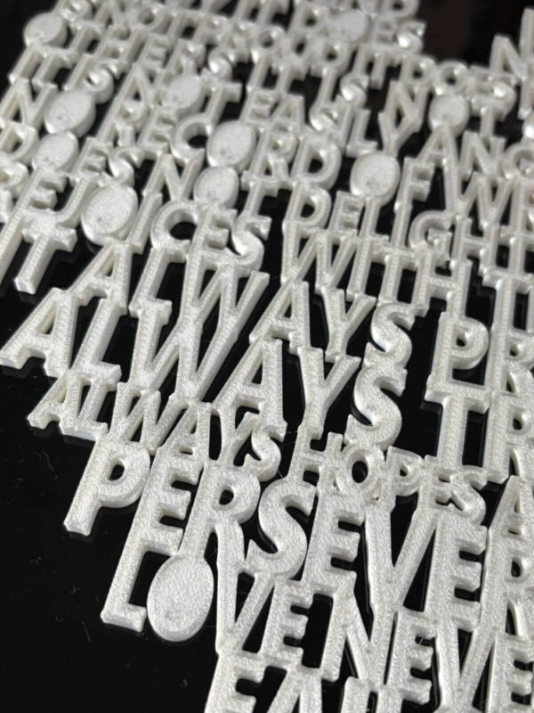 Close-up of raised 3D printed lettering on 1 Corinthians 13 scripture heart wall art — pearlescent white PLA showing "Always Trusts, Always Hopes, Perseveres, Love Never Fails