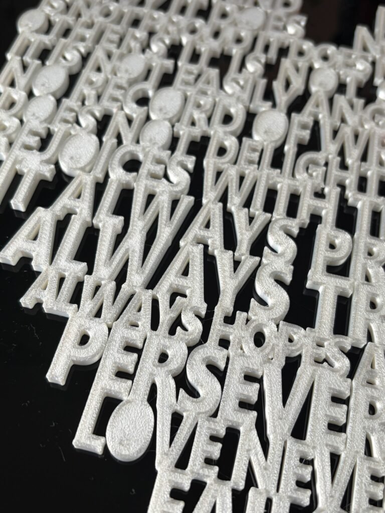 Close-up of raised 3D printed lettering on 1 Corinthians 13 scripture heart wall art — pearlescent white PLA showing "Always Trusts, Always Hopes, Perseveres, Love Never Fails