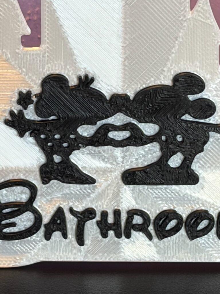 Close-up detail of 3D printed enchanted mouse couple and custom storybook text on personalised castle room sign — black PLA character on white castle background
