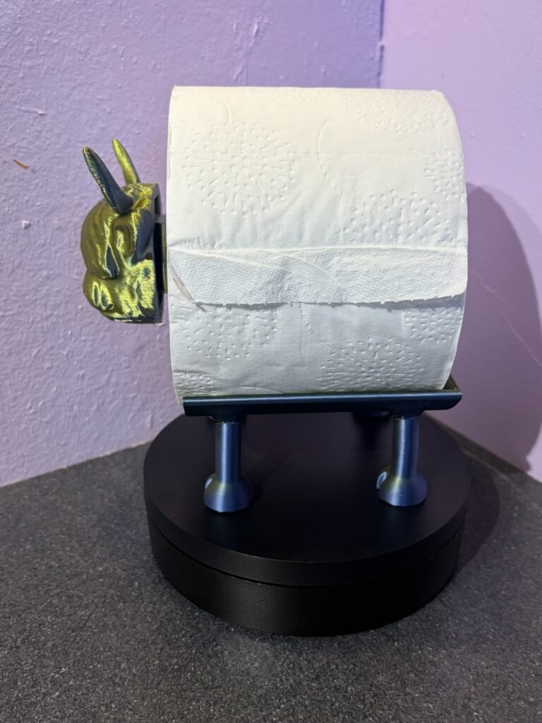 Side view of highland cow toilet roll holder holding a standard loo roll — freestanding 3D printed bathroom accessory in gold and blue PLA