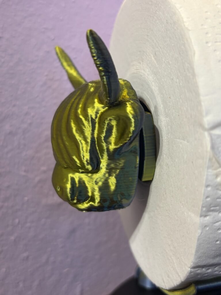 Detail shot of gold silk PLA highland cow head with horns and shaggy fringe on novelty 3D printed toilet roll holder, UK made