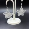 Pair of white star radial dangle earrings on display stand - 3D printed celestial jewellery by HulkyWears UK