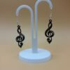 Pair of black treble clef dangle earrings on display stand - 3D printed music jewellery by HulkyWears UK