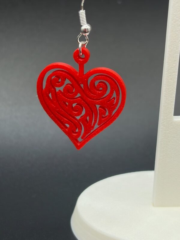Pair of red filigree heart dangle earrings on display stand - 3D printed romantic jewellery by HulkyWears UK