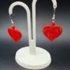 Pair of red filigree heart dangle earrings on display stand - 3D printed romantic jewellery by HulkyWears UK