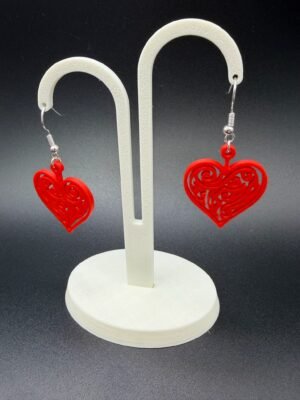 Pair of red filigree heart dangle earrings on display stand - 3D printed romantic jewellery by HulkyWears UK