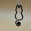 Close-up of black open cat silhouette dangle earring with curled spiral tail and silver hypoallergenic hook - HulkyWears 3D printed jewellery