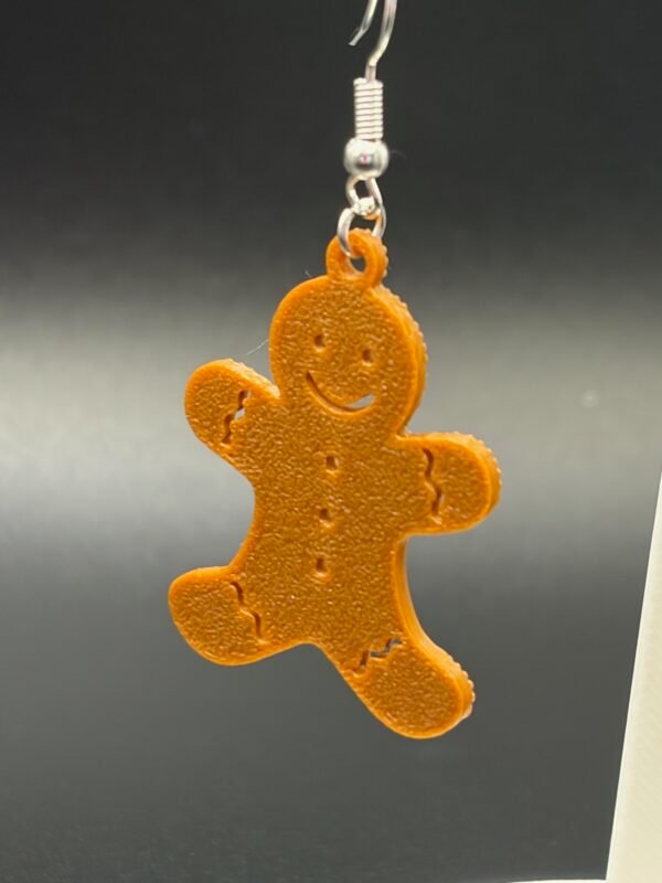 Close-up of gingerbread man dangle earring showing embossed smile, buttons and icing detail - HulkyWears 3D printed Christmas jewellery