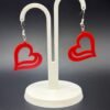 Pair of red open wave heart dangle earrings on display stand - 3D printed EcoPlastic jewellery by HulkyWears UK