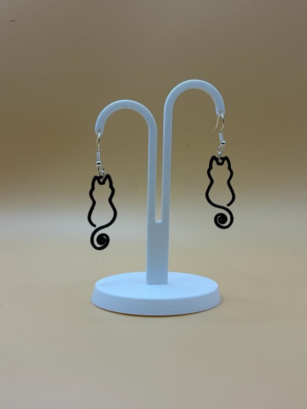 Pair of black cat silhouette dangle earrings with spiral tail on display stand - 3D printed EcoPlastic jewellery by HulkyWears UK