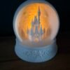 img 9526 Light up Cinderella Castle snow globe – white 3D printed Magic Kingdom castle inside a bauble with snowflakes and trees, glowing with a warm LED tea light on an ornate star base